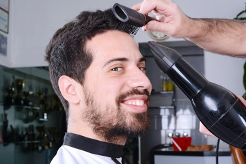 Man in hairdressing and drying his hair with a hairdryer.