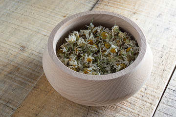 Dried chamomile in wooden bowl