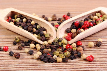 Fresh colored pepper with spoon on wooden background