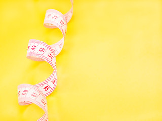 White measuring tape on yellow background