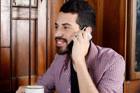 Man talking on phone and drinking coffee.
