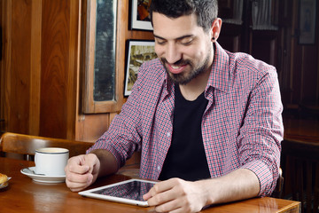 Fototapeta na wymiar Young man using digital tablet at a cafe.