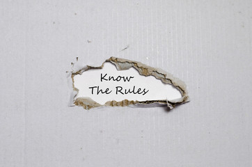 The words know the rules appearing behind torn paper
