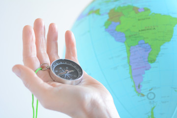 Hand holding a compass with South America on a globe