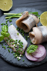 Closeup of herring rolls with green and red onion and lime