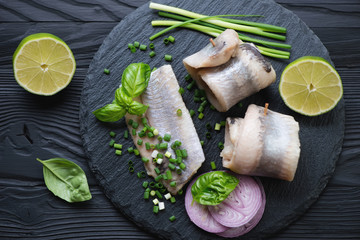 Herring fillet rolls on a stone slate tray, above view, close-up