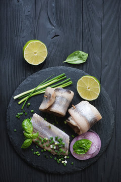 Top view of a stone slate with herring fillet, onion and lime