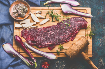 Raw beef chop with wooden meat Tenderizer and cooking ingredients on cutting board, top view