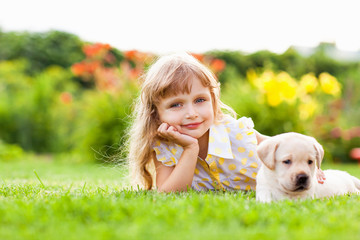 Little girl with a labrador puppy, outdoor summer