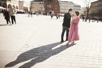 Obraz premium wedding. beautiful couple, bride with pink dress walking in the old city Krakow, their shadows