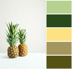 Ripe pineapples on a white wooden table with color palette