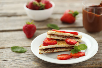 French toasts with chocolate and strawberry on wooden table