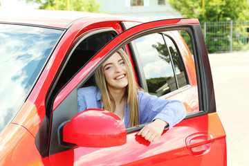 Beautiful young girl sitting in red car