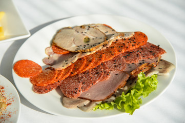 Cold meat appetizer on a plate. Sausage sausage and pork slices. Served food to the table.