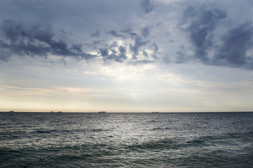 Naklejka na ściany i meble Seascape with ships on the horizon and cloudy sky