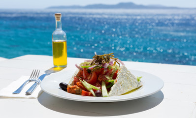 Griechischer Salat und Olivenöl vor glitzerndem Meer