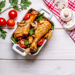 Chicken legs fried with mushrooms and tomatoes.