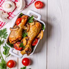 Chicken legs fried with mushrooms and tomatoes.