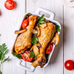 Chicken legs fried with mushrooms and tomatoes.