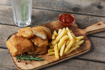  chicken nuggets french fries on the board with red sauce