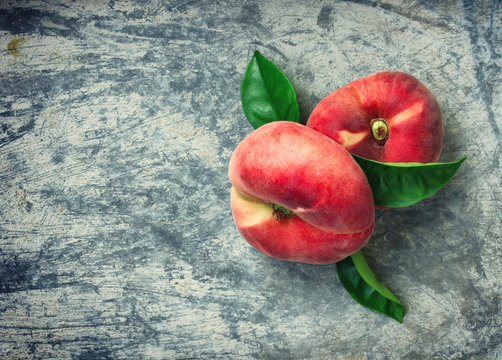 two flat peaches with leaves