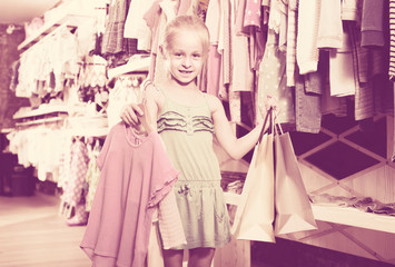 Fototapeta na wymiar portrait of girl standing in kids clothes store with shopping b