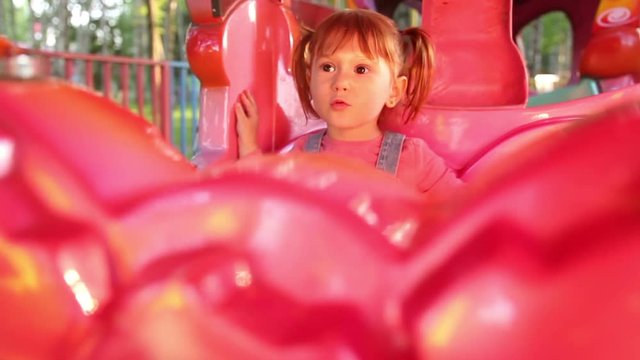 Redhead baby girl child riding toy train in luna park.