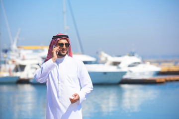 Arabian man talking on the cell phone at the yacht harbor