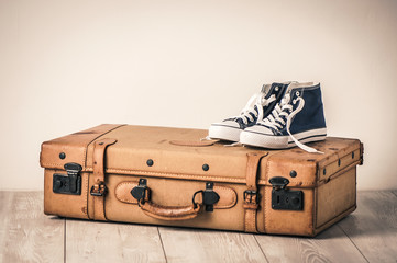 Sneakers on top of an old brown suitcase with a retro effect