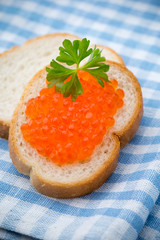 Bread with fresh cream cheese and red caviar on table.