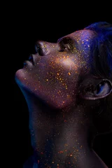 Leuchtendes Neon-Make-up mit dramatischem Blick in seinen Augen. Kreative Körperkunst zum Thema Weltall und Sterne. Erstaunliches Nahaufnahmeporträt, das im dunklen Make-up leuchtet. © korabkova1
