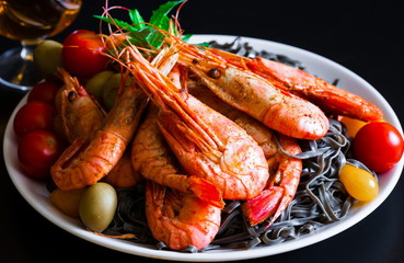 Food. black pasta, shrimps, cherry tomatoes, black background