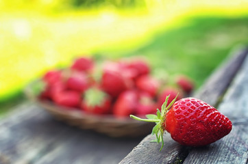 Strawberry in wicker plate on wooden background