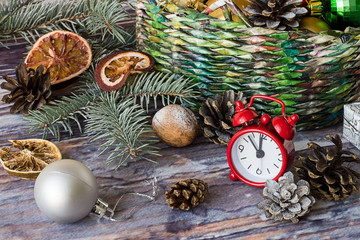 Preparing for Christmas.   Wicker basket with Christmas ornaments, spruce branch, watches, cones and dried slices of orange on old wooden table.