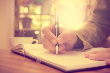 Man hand holding a pen writing on the notebook, Vintage style.
