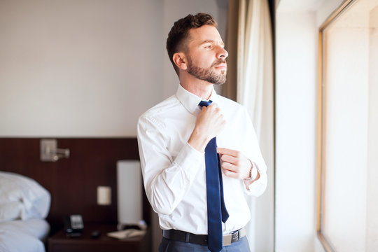 Businessman fixing his tie in a hotel room
