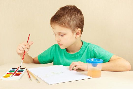 Young artist in a green shirt painting colors