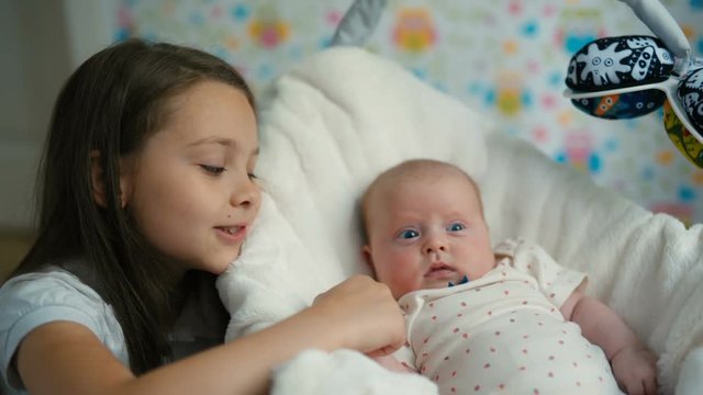 the little girl looks at her baby sister
