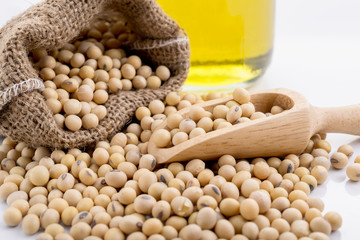 Delicious soybeans spilling from a burlap sack with a scoop, accompanied by a bottle of oil,...