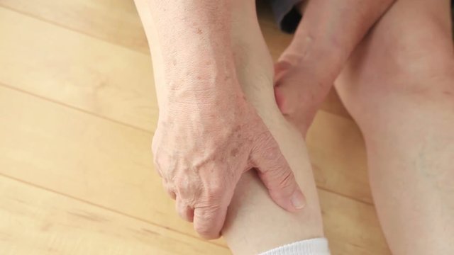 An older man rubs a painful muscle in his leg