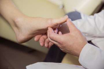 the hands of the doctor examines the foot of a patient