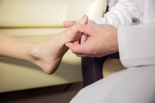 the hands of the doctor examines the foot of a patient