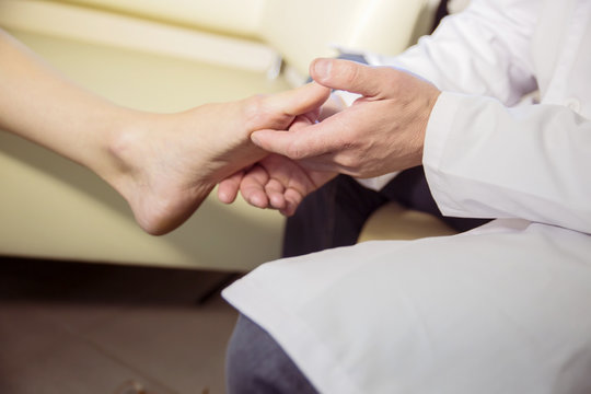 the hands of the doctor examines the foot of a patient