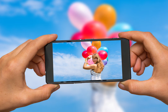 Taking photo of lady with balloons with mobile phone