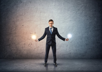 Fototapeta premium Front view of a businessman standing and holding glowing light bulbs in both hands