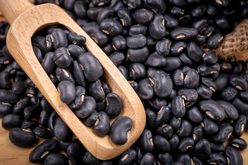 Sack of black beans spill beans with black beans in a wooden spo