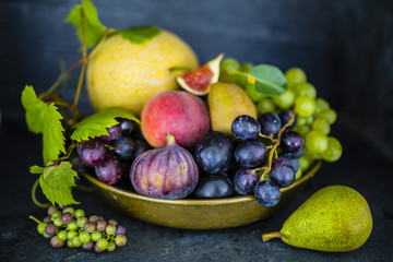 Beautiful still life with grapes and figs and other fruits on stone background.