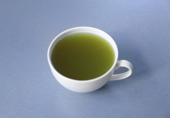 Cup of green matcha tea on color background