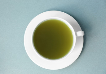 Cup of green matcha tea on color background