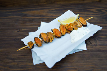 Grilled seafood kebab with sauce and lemon. Mussels on stick. Street food barbeque. - 118758367